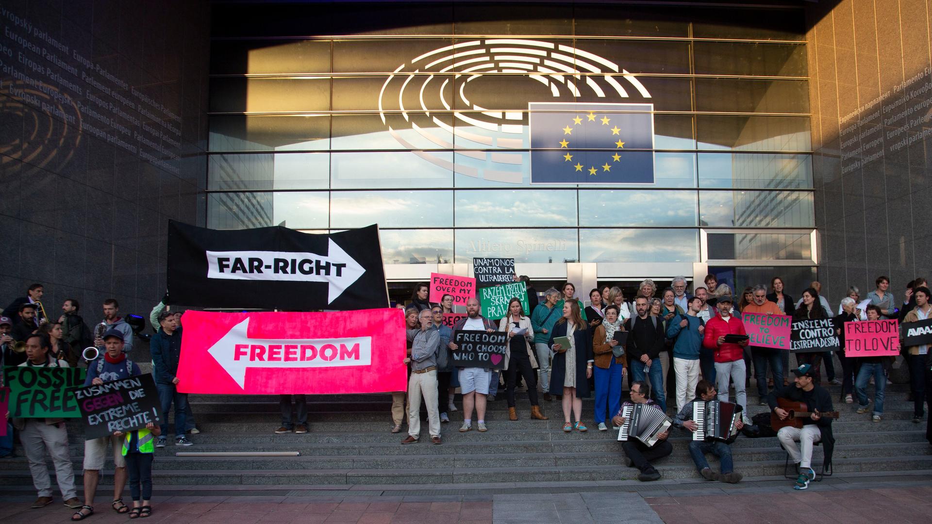 Protest gegen Rechts auf den Stufen des Europäischen Parlaments. Demonstranten halten große Pfeile, die in unterschiedliche Richtungen zeigen und mit "Far-Right" und "Freedom" beschriftet sind.
