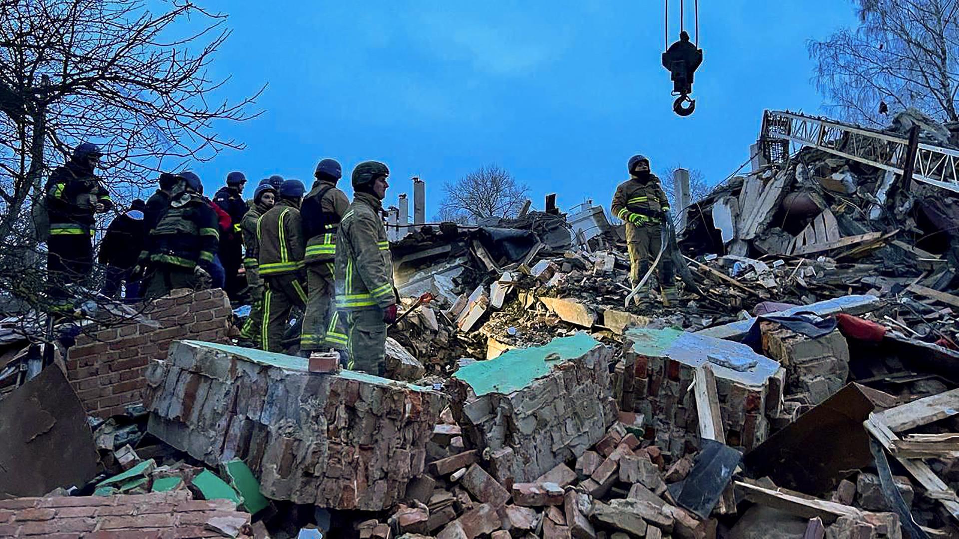 Einsatz- und Rettungskräfte stehen in den Trümmern eines Hauses.