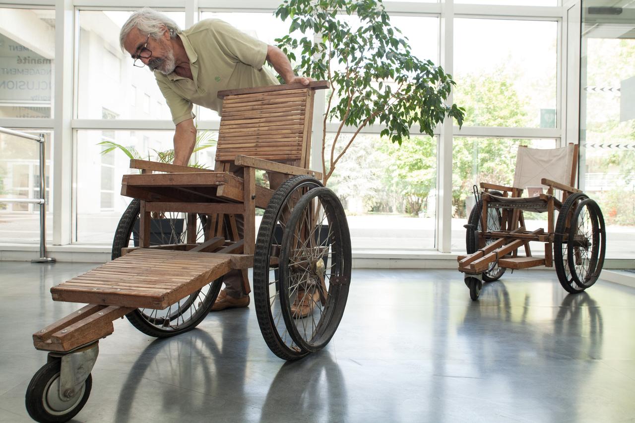 Jean-Baptiste Richardier. Ein älterer Herr mit Brille und Bart bewegt einen Rollstuhl aus Holz. 