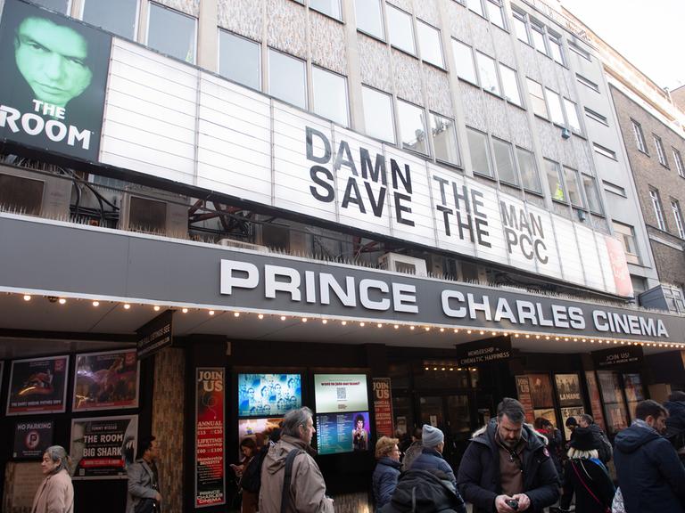 Das Prince Charles Cinema in London. Vor dem Eingang stehen Menschen. Auf der Anzeigetafel wird zur Rettung des Kinos aufgerufen.