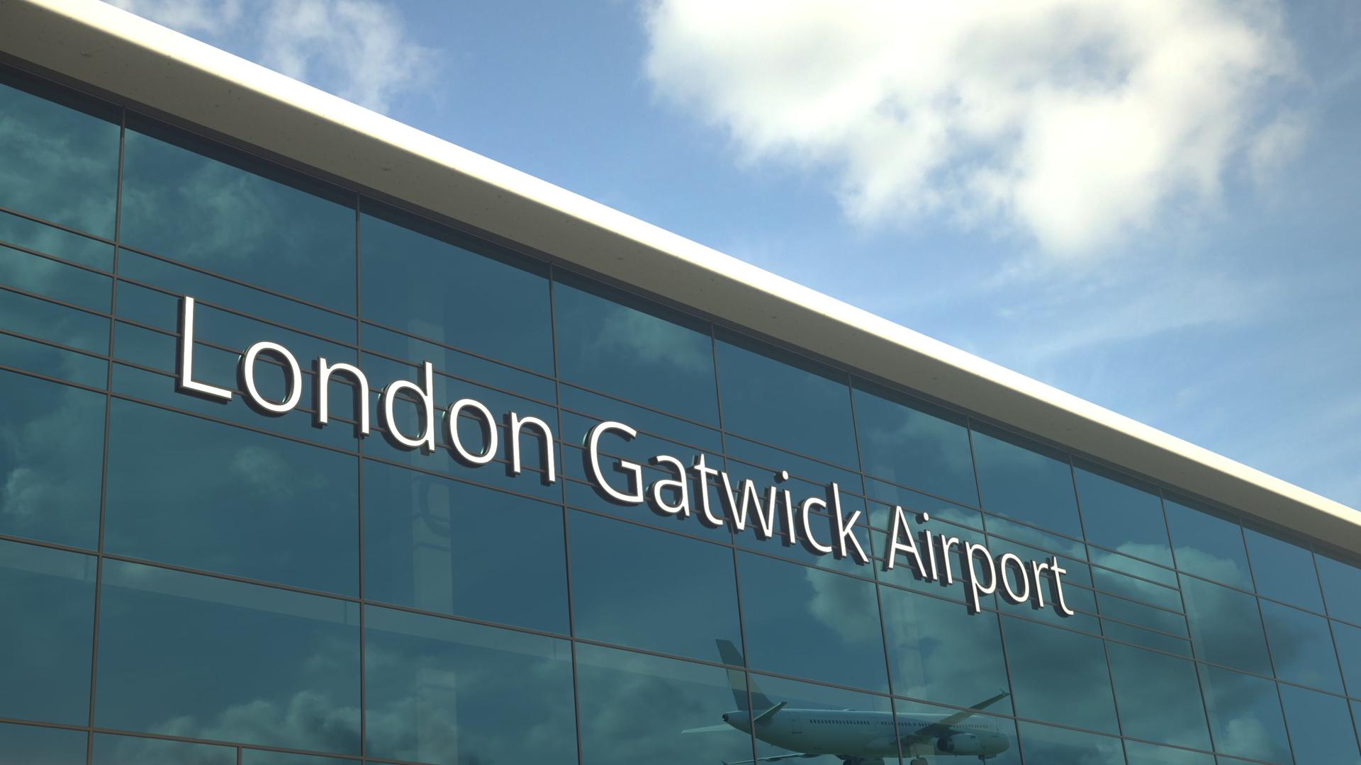 In der großen Fensterfront von London Gatwick Airport spiegelt sich ein landendes Flugzeug.