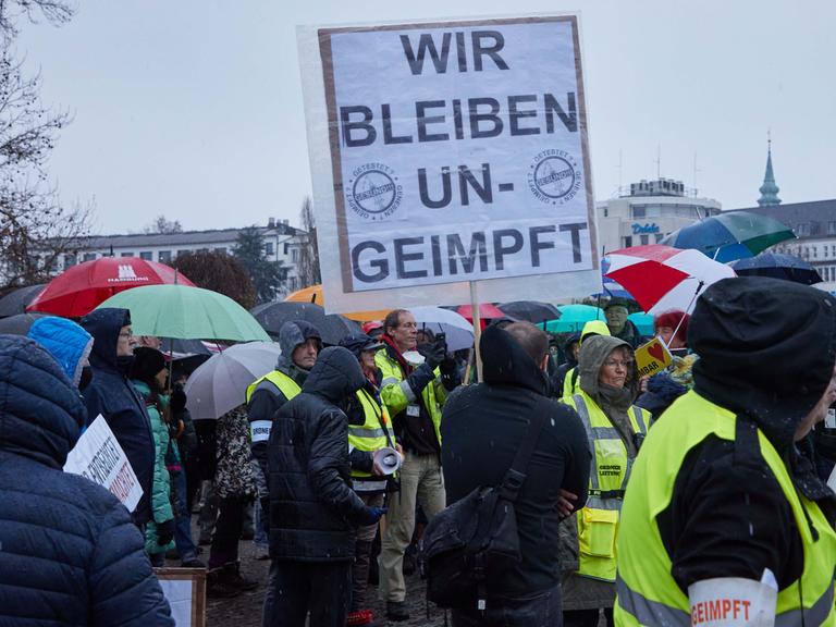 Ein Teilnehmer einer Demonstration von Corona-Impfgegnern hält ein Transparent mit den Aufschrift "Wir bleiben ungeimpft".