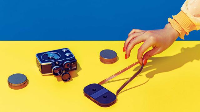 Pop Art Fotografie: Stilisiertes blau-gelbes Bild einer Retro-Kamera und einer Kassette, die eine weibliche Hand mit spitzen Fingern und lackierten Nägeln anfasst.