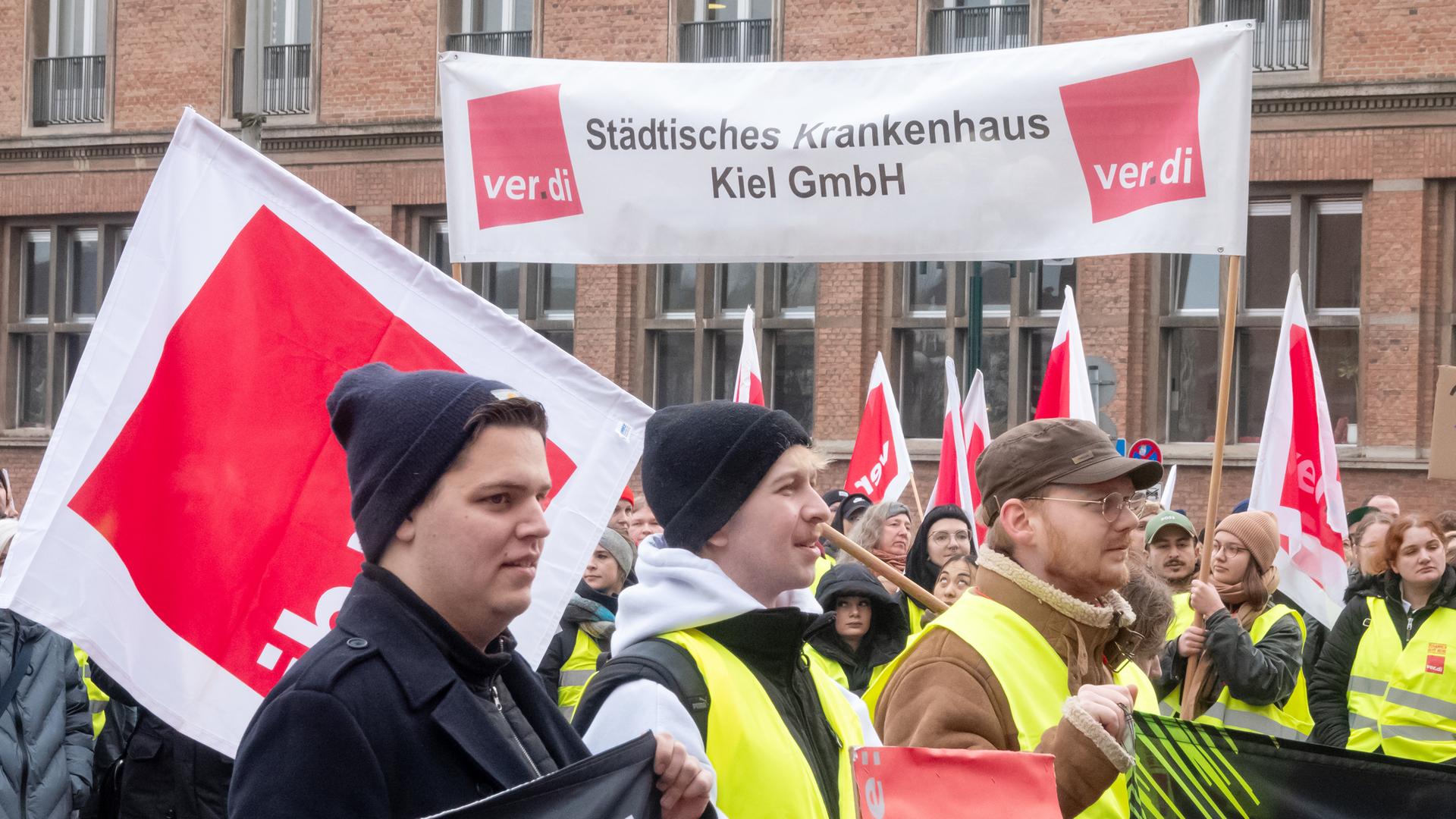 Streikende, darunter vom Städtischen Krankenhaus, stehen am Vormittag bei einer Kundgebung während eines Warnstreiks auf dem Rathausplatz in Kiel. 