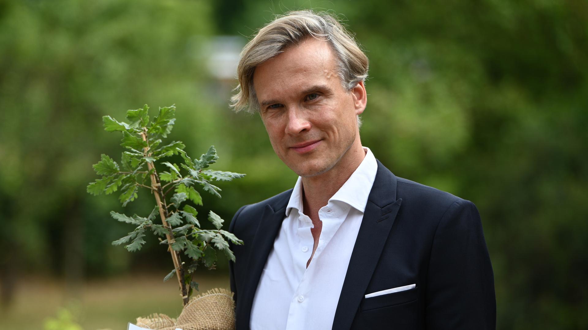 Stefan Körner, Vorstand der Stiftung Fürst-Pückler-Museum Park und Schloss Branitz, hält im Juni 2025 einen Setzling. Mithilfe eines Förderprogramms von EU und brandenburgischem Kulturministerium sollen klimabedingte Schäden erfasst und reduziert werden. 