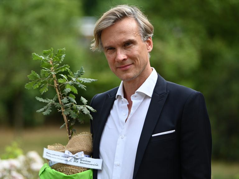 Stefan Körner, Vorstand der Stiftung Fürst-Pückler-Museum Park und Schloss Branitz, hält im Juni 2025 einen Setzling. Mithilfe eines Förderprogramms von EU und brandenburgischem Kulturministerium sollen klimabedingte Schäden erfasst und reduziert werden. Stefan Körner, Vorstand der Stiftung Fürst-Pückler-Museum Park und Schloss Branitz, hält im Juni 2025 einen Setzling. Mithilfe eines Förderprogramms von EU und brandenburgischem Kulturministerium sollen klimabedingte Schäden erfasst und reduziert werden.