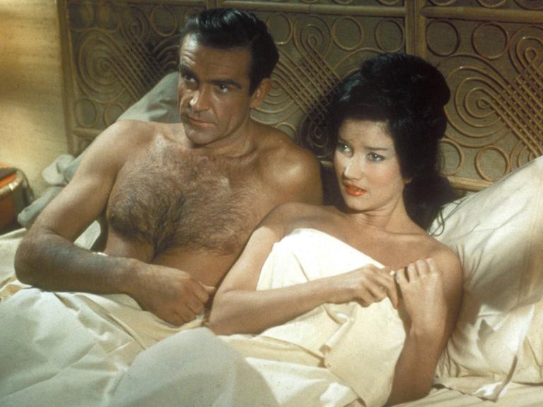 Szene aus dem James-Bond-Film "Dr. No": Der Schauspieler Sean Connery als Agent 007 liegt neben einer Frau in einem Bett.