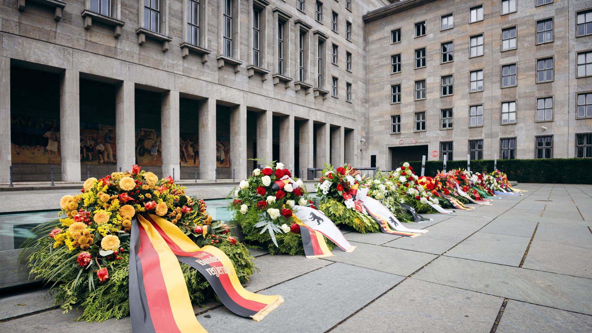 Vor dem Bundesfinanzministerium liegen mehrere Kränze. Im Vordergrund mit schwarz-rot-goldener Schleife, im Hintergurnd mit Berliner Wappen. Vor dem Bundesfinanzministerium liegen mehrere Kränze. Im Vordergrund mit schwarz-rot-goldener Schleife, im Hintergurnd mit Berliner Wappen.