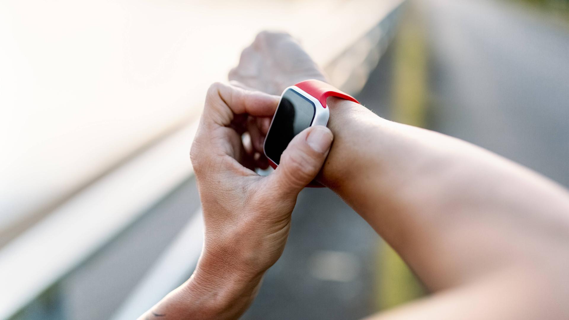 Ein Sportler tippt auf seiner Smartwatch am Handgelenk, seinem Notfallarmband.