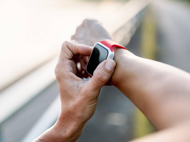 Ein Sportler tippt auf seiner Smartwatch am Handgelenk, seinem Notfallarmband.
