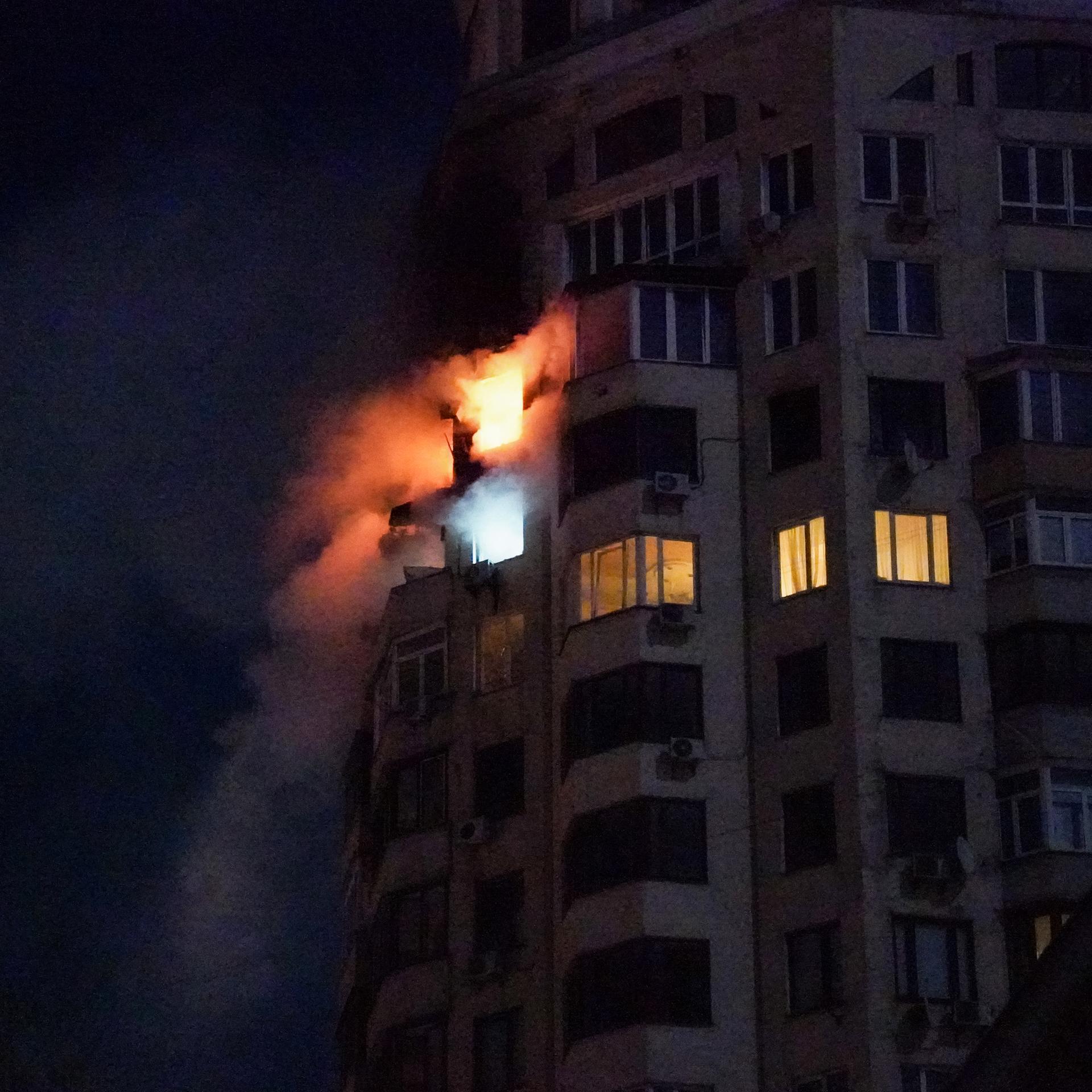 Aus den Fenstern zweier Wohnungen in einem mehrstöckigen Haus in Kiew schlagen die Flammen aus dem Fenster.