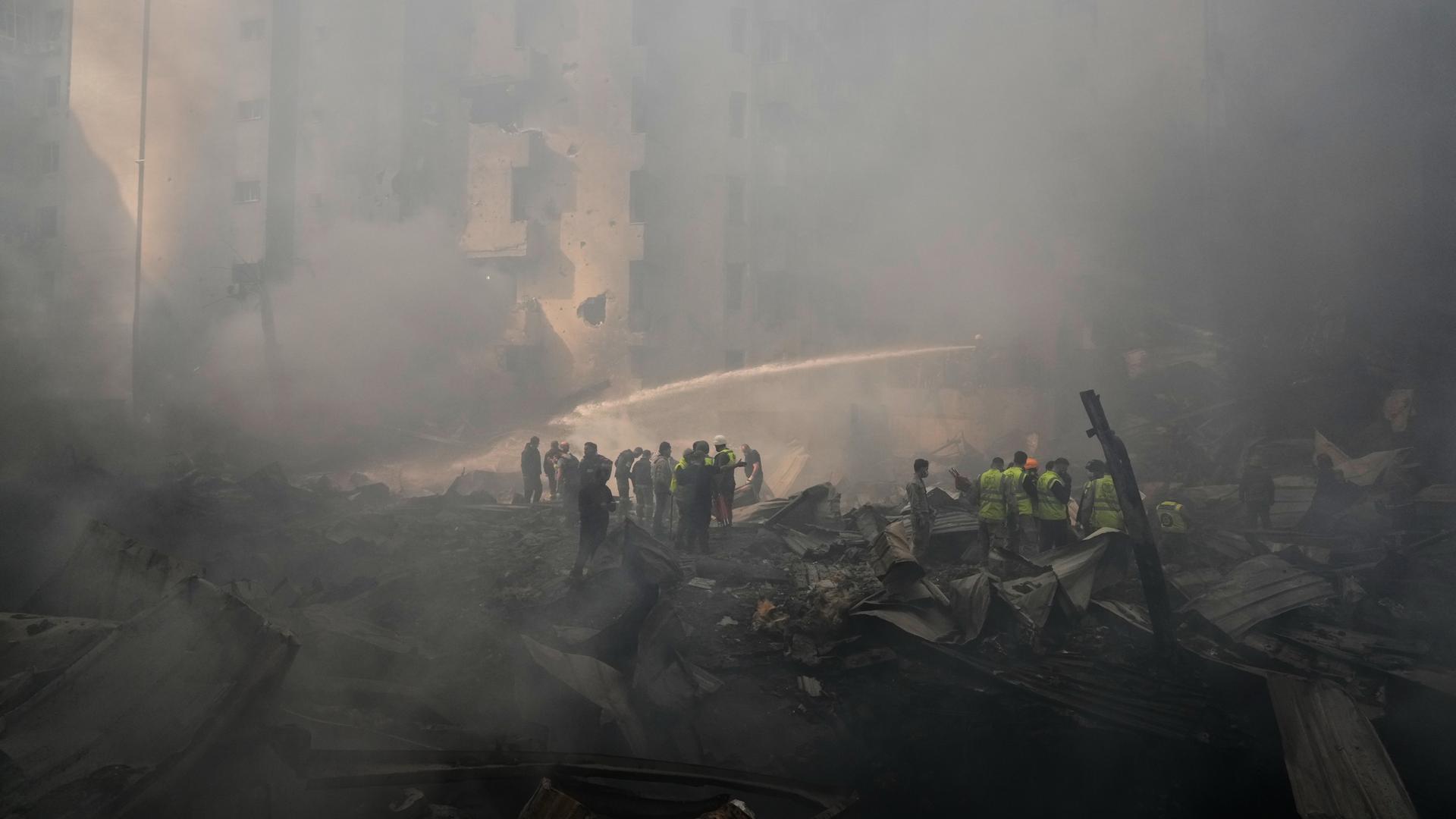 Feuerwehrleute und Anwohner versuchen nach einem israelischen Angriff Feuer zu löschen. Die Luft ist voller Qualm. Feuerwehrleute und Anwohner versuchen nach einem israelischen Angriff Feuer zu löschen. Die Luft ist voller Qualm.