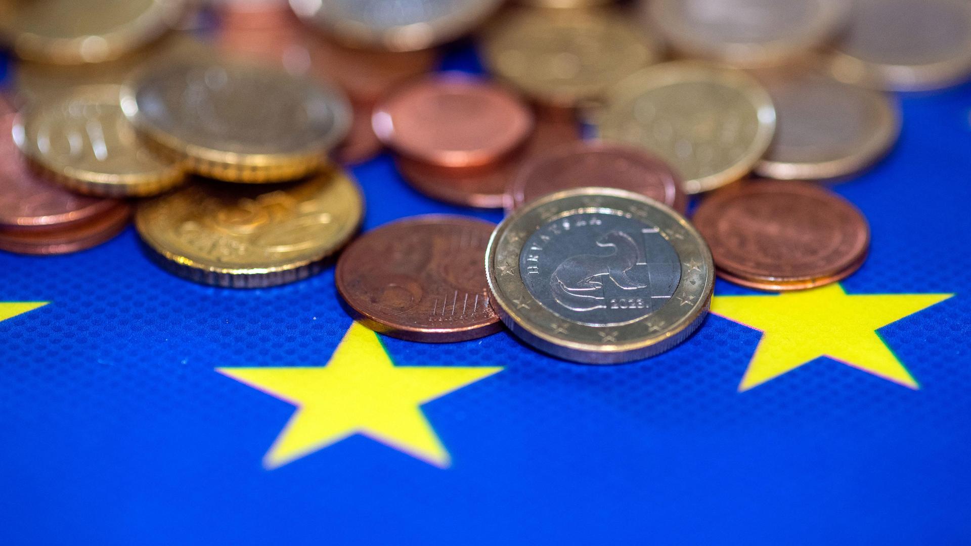 Euromünzen liegen auf EU-Fahne 