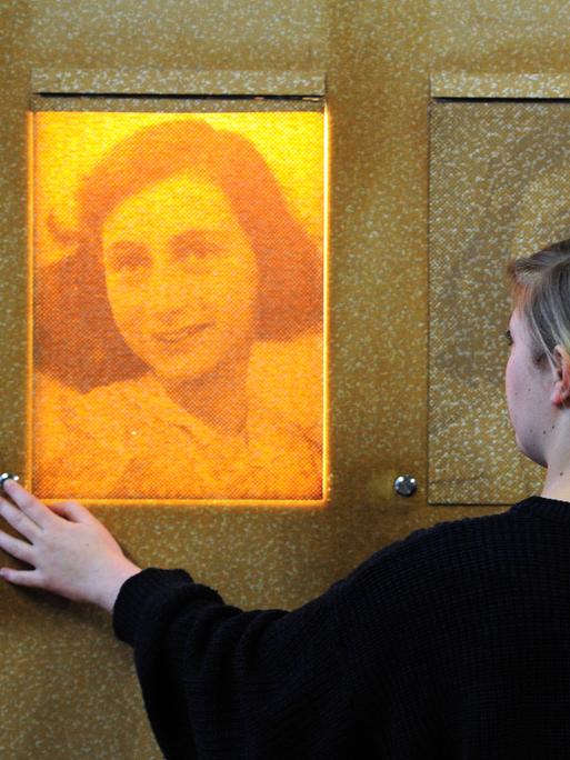 In der Bildungsstätte Anne Frank in Frankfurt am Main steht eine Frau vor einem Portrait von Anne Frank.