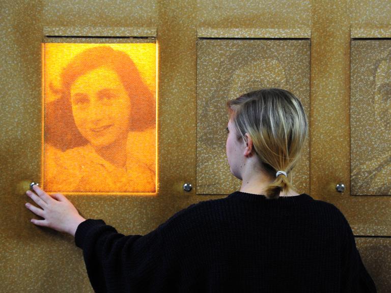 In der Bildungsstätte Anne Frank in Frankfurt am Main steht eine Frau vor einem Portrait von Anne Frank.