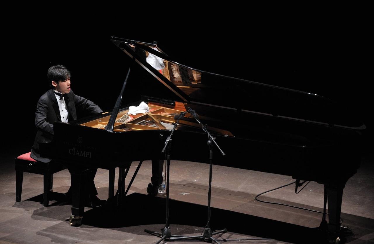Haochen Zhang sitzt an einem großen Konzertflügel und spielt vertieft.