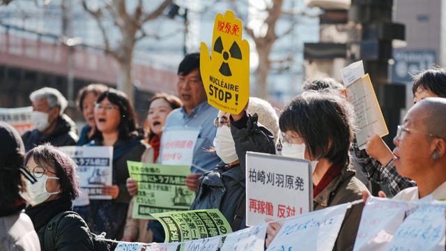 Eine Gruppe von Demonstrierenden, einige halten Banner unter anderem mit der Aufschrift "Stop Nuklear" in die Luft.