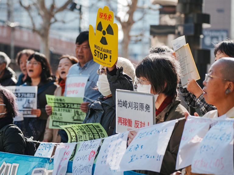 Eine Gruppe von Demonstrierenden, einige halten Banner unter anderem mit der Aufschrift "Stop Nuklear" in die Luft. Eine Gruppe von Demonstrierenden, einige halten Banner unter anderem mit der Aufschrift "Stop Nuklear" in die Luft.