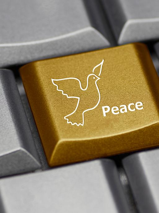 Eine graue Computer-Tastatur mit einer goldenen Friedenstaube darauf