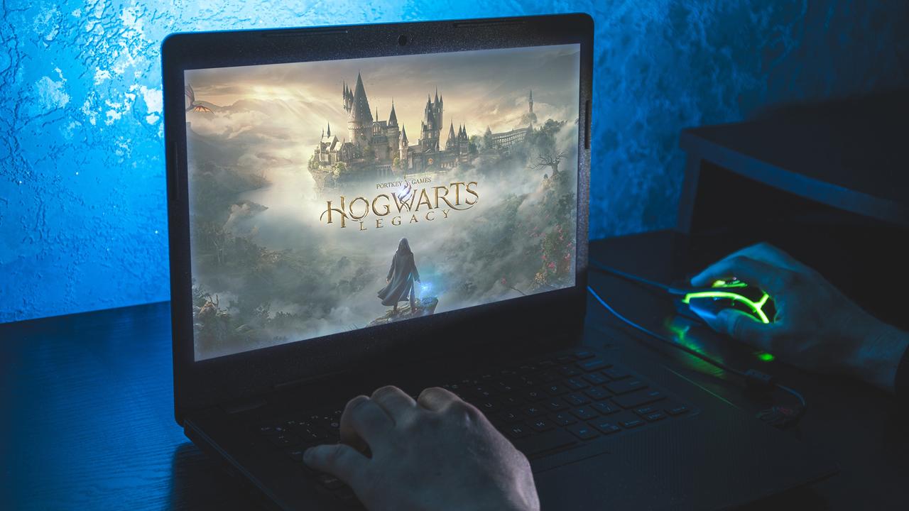 Ein Mensch sitzt vor einem Bildschirm auf dem das Spiel "Hogwarts Legacy" zu sehen ist.