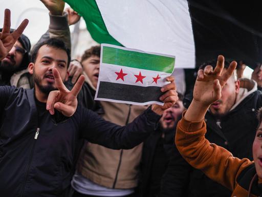 Syrer jubeln, zeigen das Peace-Zeichen und zeigen eine syrische Flagge (Ankara, Türkei am 8.12.2024)