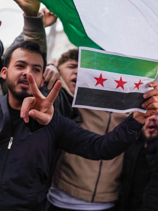 Syrer jubeln, zeigen das Peace-Zeichen und zeigen eine syrische Flagge (Ankara, Türkei am 8.12.2024)