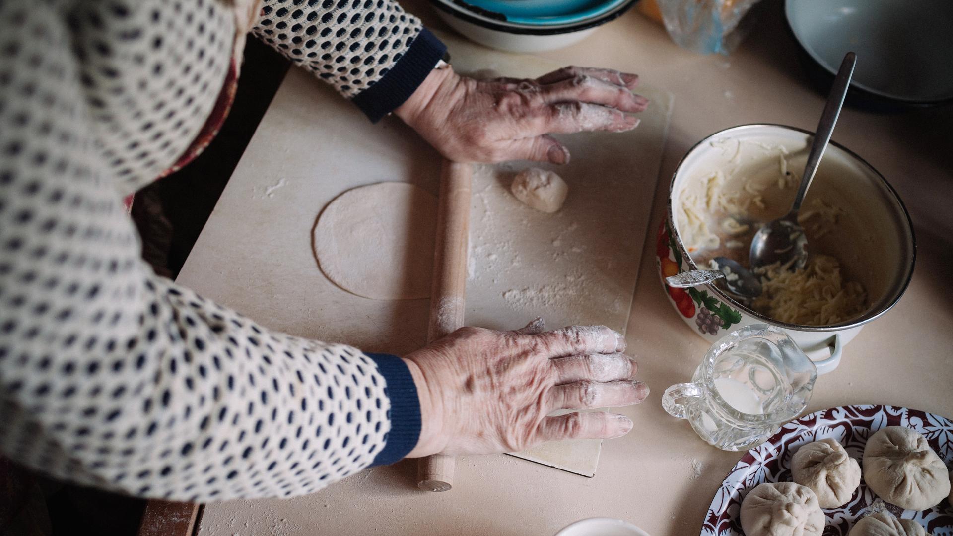 Hände einer ukrainischen Seniorin, die ein Nationalgericht kocht.
