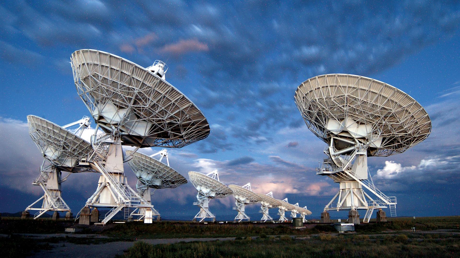 Eine Freiluftanlage mit großen Teleskop-Antennen, die auf den Himmel gerichtet sind.