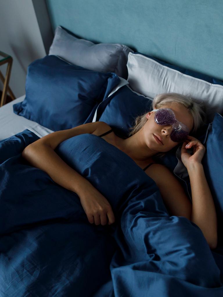 Eine Frau liegt mit Augenmaske im Bett und schläft. (Symbolfoto)