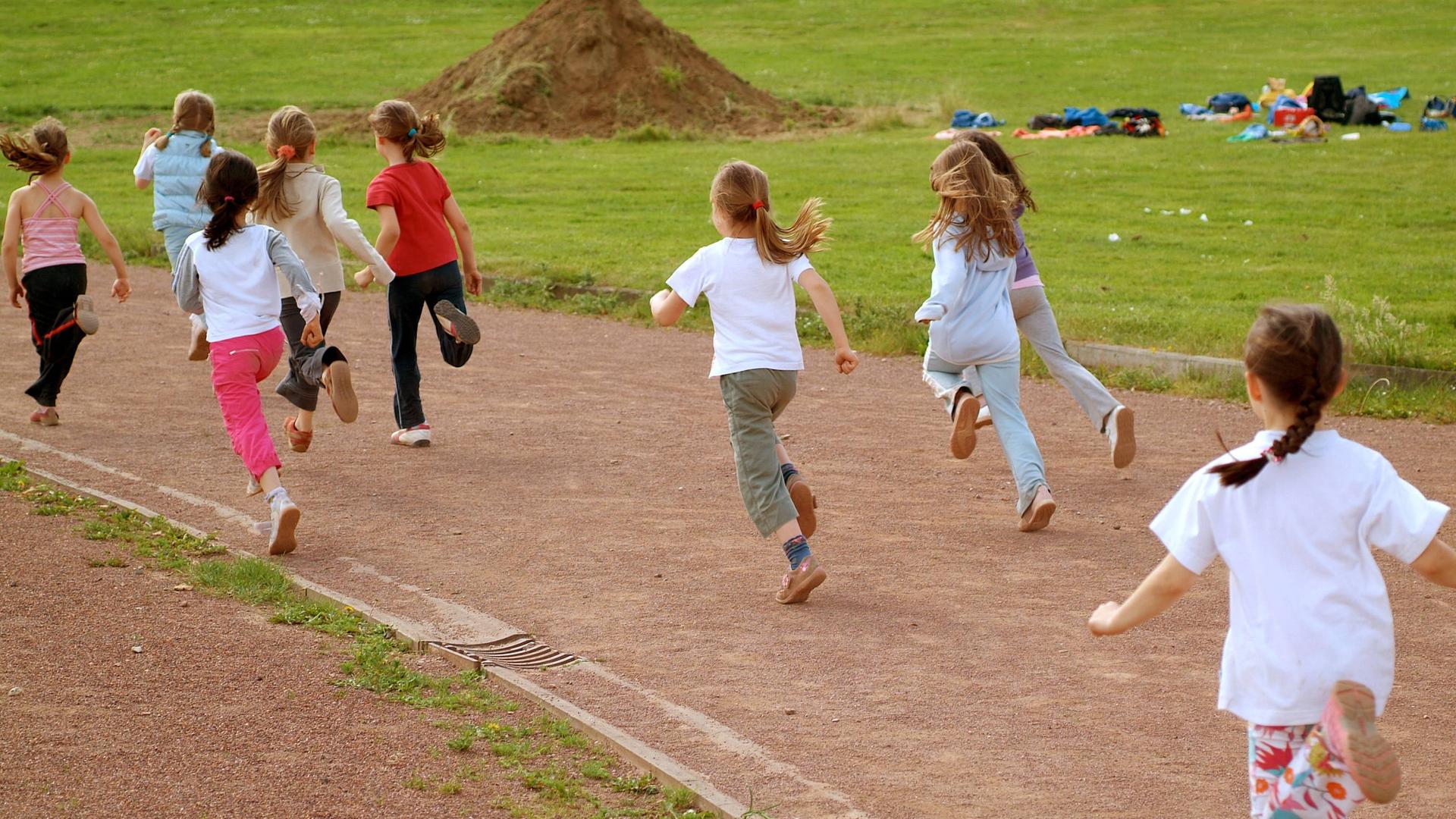 Kinder rennen auf einer Lauf-Bahn.