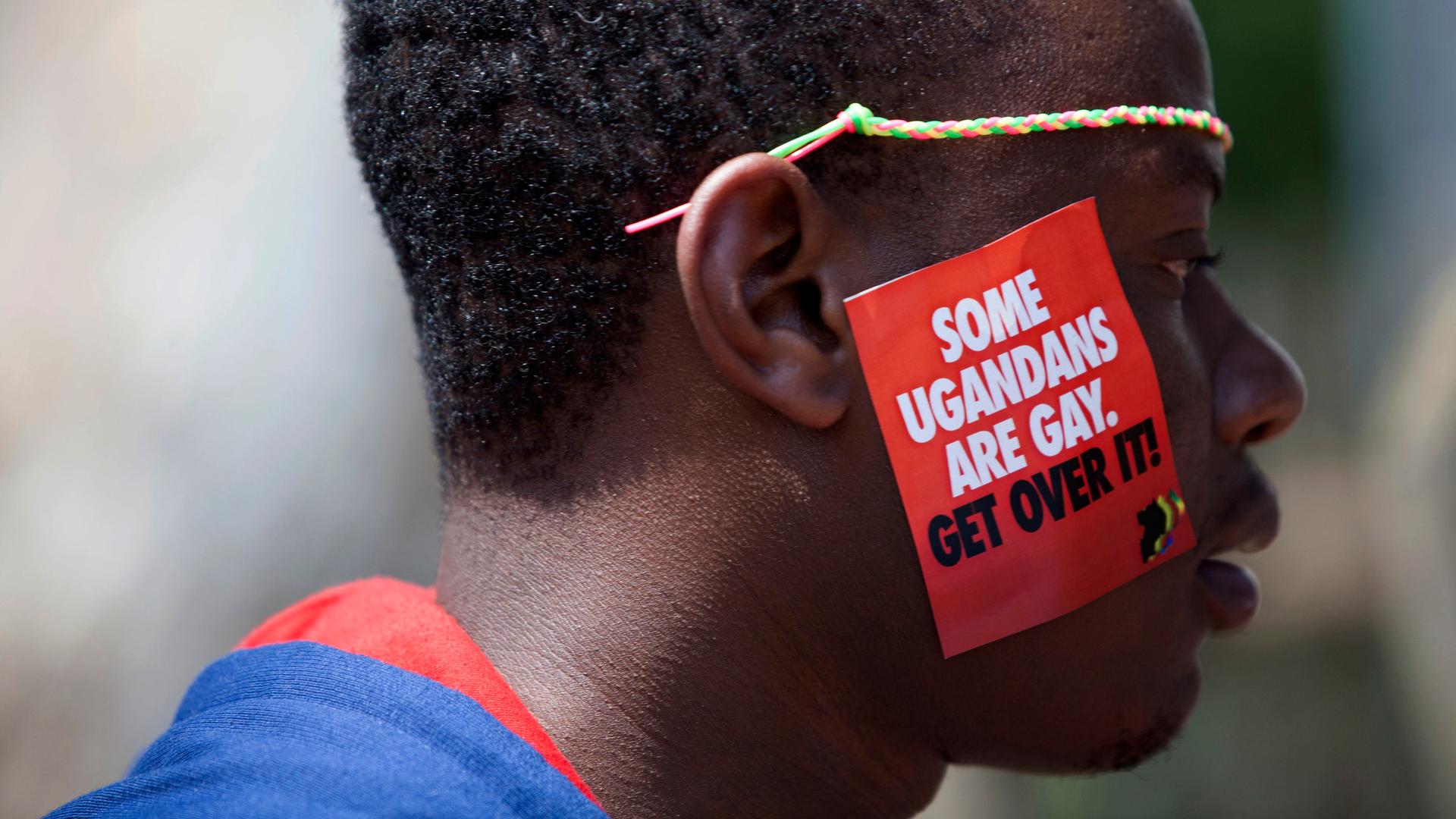 Ein Mann trägt auf seiner Wange einen Aufkleber, auf dem steht: „Some Ugandans are gay. Get over it.“