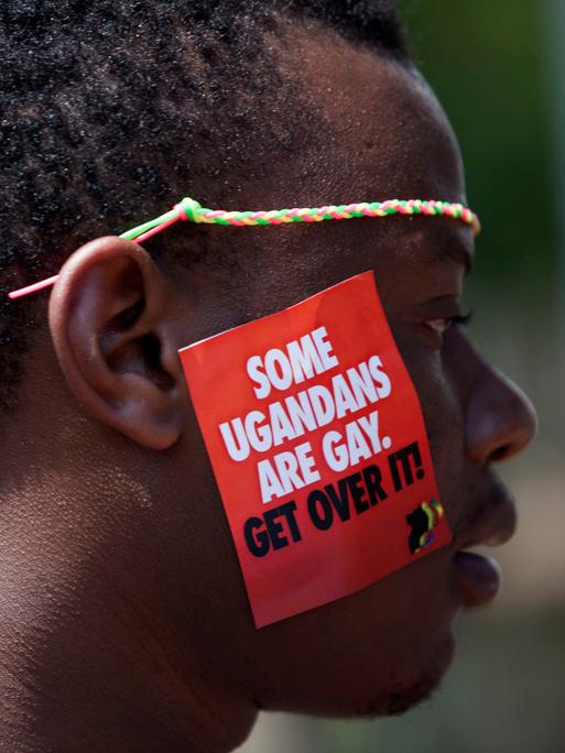 Ein Mann trägt auf seiner Wange einen Aufkleber, auf dem steht: „Some Ugandans are gay. Get over it.“