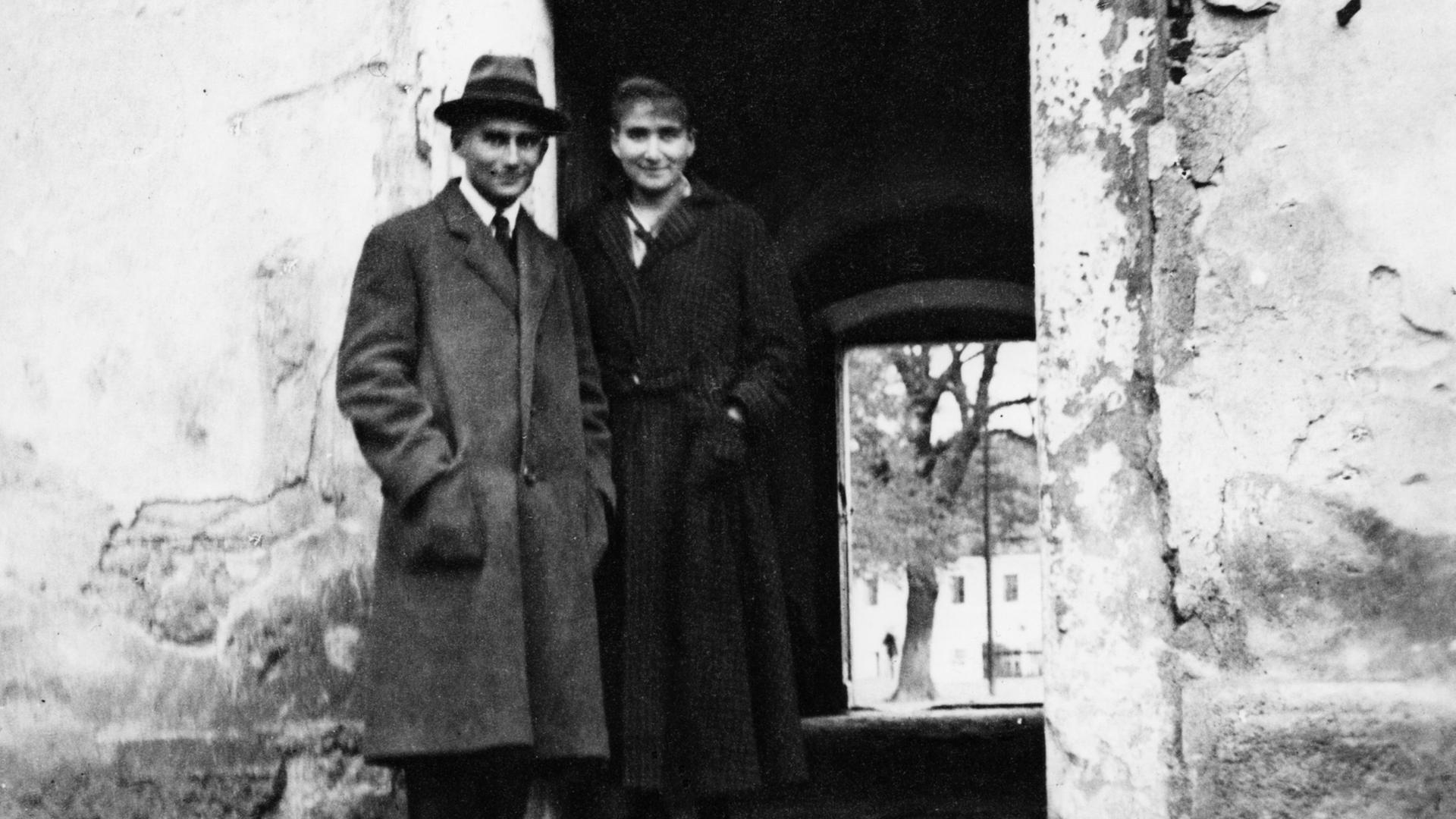 Historisches Schwarzweißfoto von Franz Kafka und seiner Schwester Ottla, die nebeneinander in einem Türrahmen stehen.