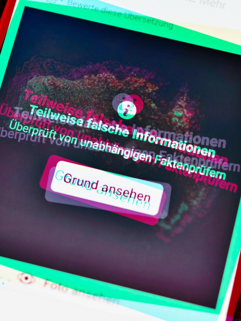Ein Smartphone mit aufgedeckter Falschinformation in einem sozialen Netzwerk. Die Farbgebung ist an Tik Tok angelehnt.