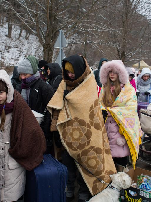 Ukrainische Flüchtlinge warten mit Decken an der polnischen Grenze auf ihre Einreise.