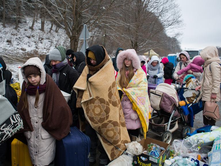 Ukrainische Flüchtlinge warten mit Decken an der polnischen Grenze auf ihre Einreise.