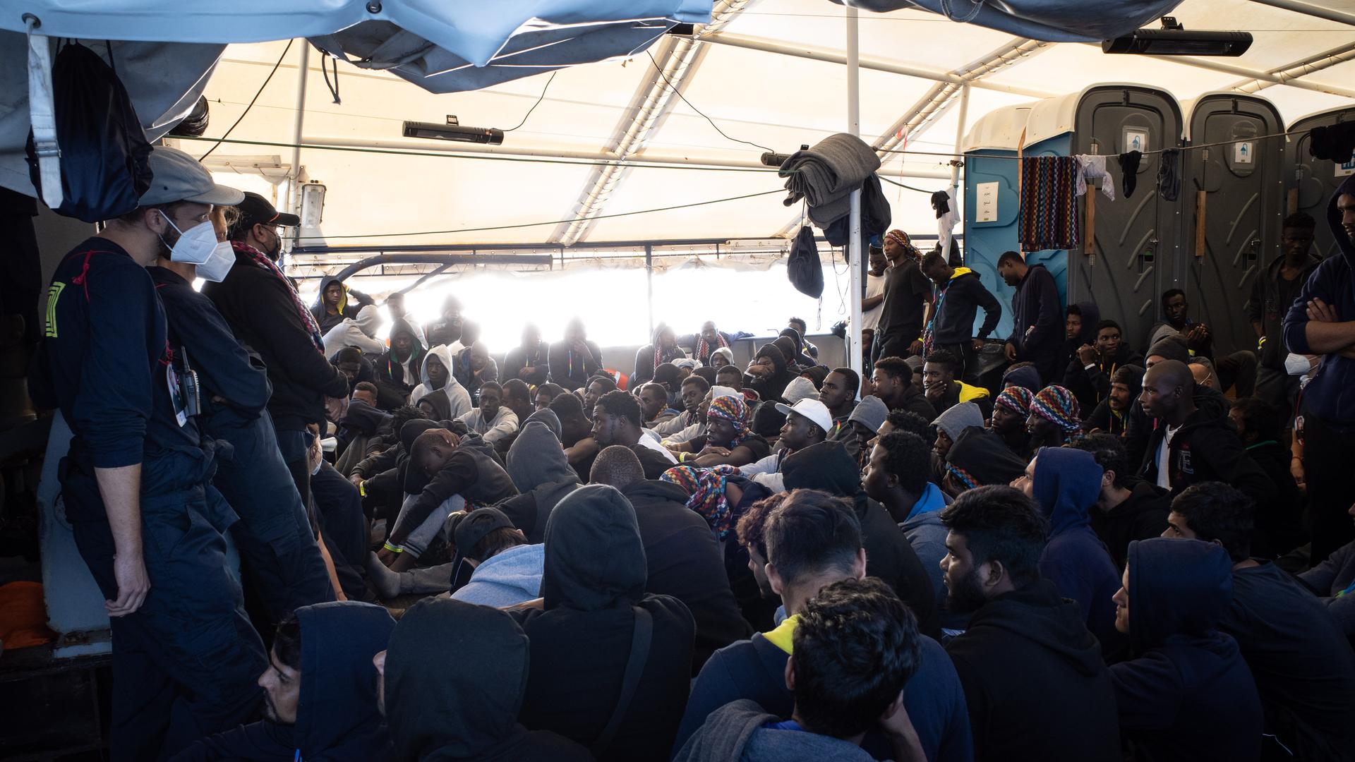 An Deck des deutschen Seenotrettungsschiffes "Humanity 1" sitzen zahlreiche aus dem Mittelmeer gerettete Geflüchtete. An Deck des deutschen Seenotrettungsschiffes "Humanity 1" sitzen zahlreiche aus dem Mittelmeer gerettete Geflüchtete.