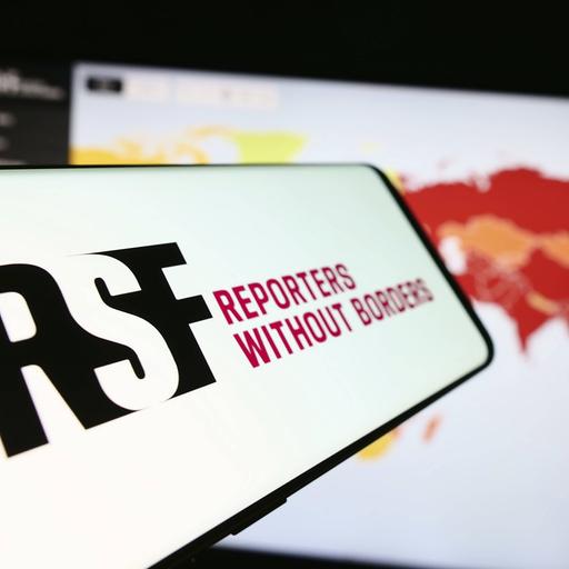 Ein Mobiltelefon mit dem Logo der internationalen Organisation Reporter ohne Grenzen vor einer Website.