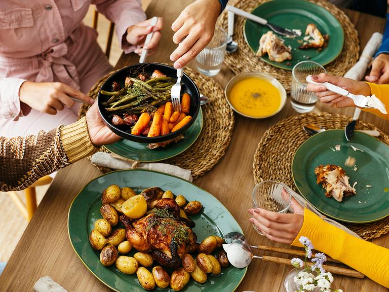 Freunde sitzen gemeinsam an einem Tisch und essen gemeinsam. 