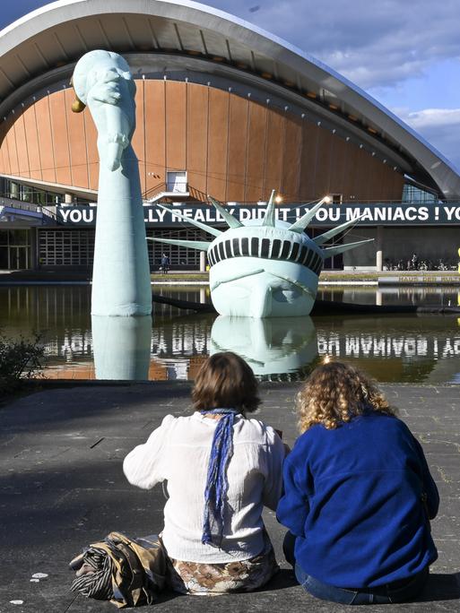 Im Rahmen der Ausstellung „Possibility of Unvernunft” in Berlin schauen zwei Besucherinnen auf eine aufblasbare Nachbildung der Freiheitsstatue, die im Brunnen vor dem Haus der Kulturen der Welt versunken ist. Im Rahmen der Ausstellung „Possibility of Unvernunft” in Berlin schauen zwei Besucherinnen auf eine aufblasbare Nachbildung der Freiheitsstatue, die im Brunnen vor dem Haus der Kulturen der Welt versunken ist.