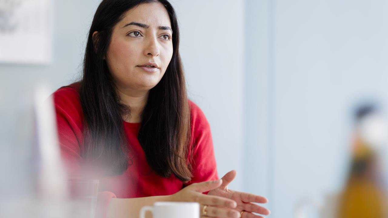 Reem Alabali-Radovan trägt ein rotes Oberteil, sitzt an einem Tisch und spricht gestikulierend.