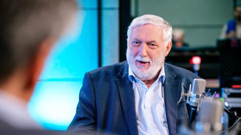 Der frühere EU-Kommissar Franz Fischler (ÖVP) sitzt in einem blauen Anzug in einer Podcastaufzeichnung. 