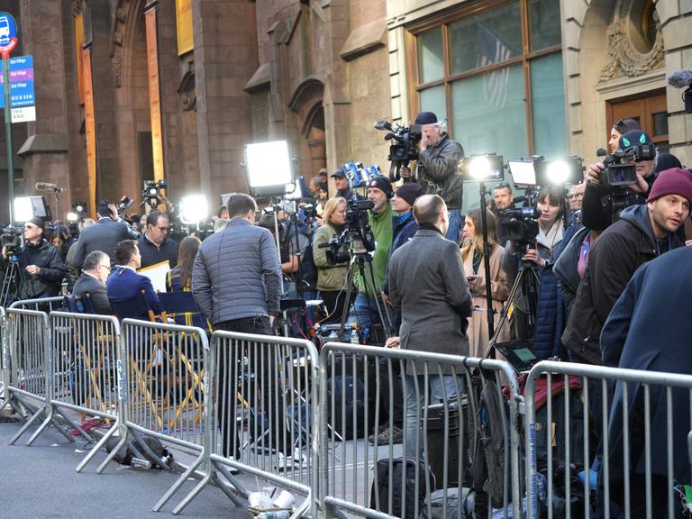 In einem abgesperrten Bereich warten viele Journalistinnen und Journalisten mit Kameras auf die Ankunft von Donald Trump.