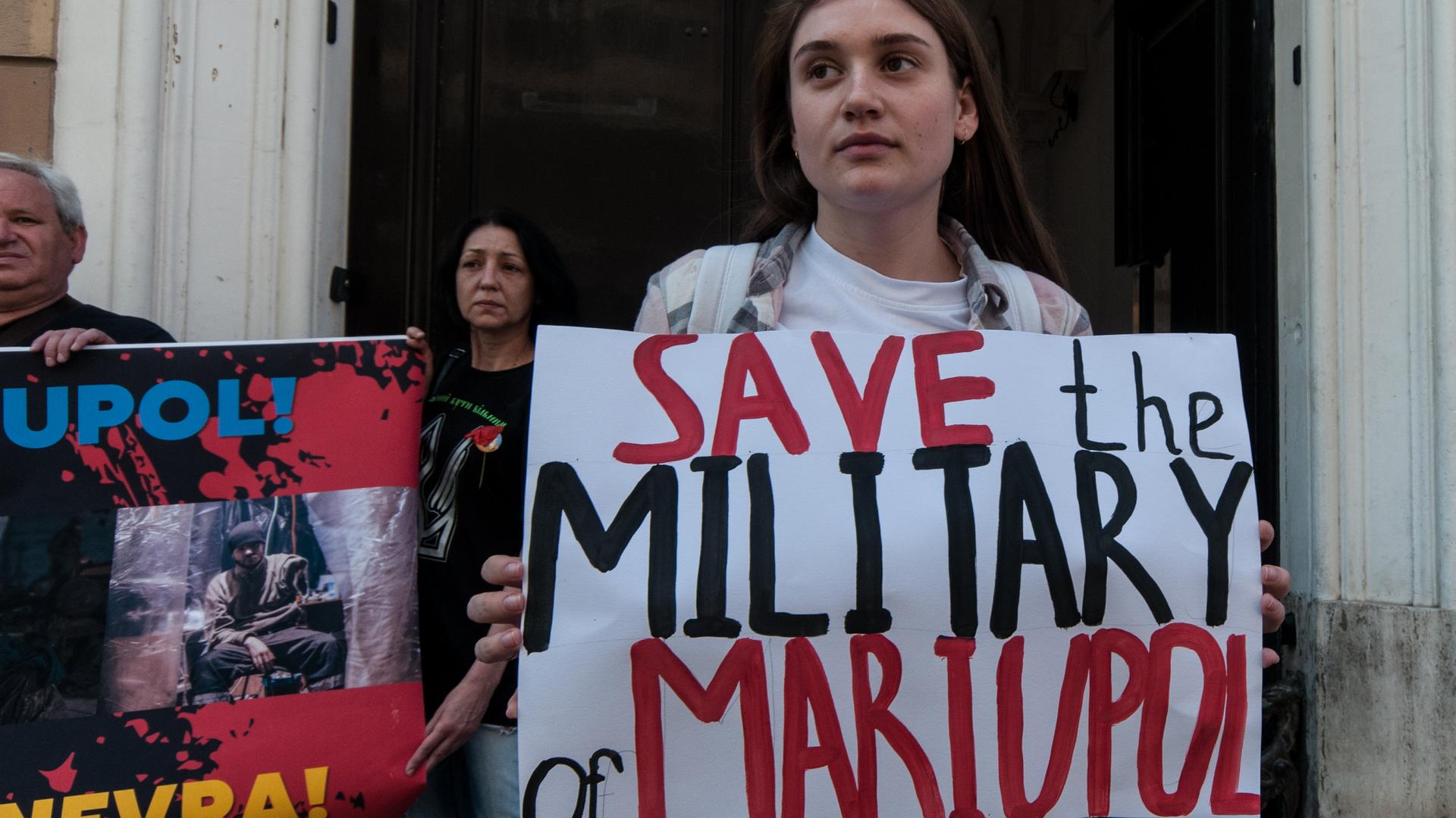 Eine Frau hält ein Schild in der Hand auf dem die Worte "Save the military of Mariupol" geschrieben sind