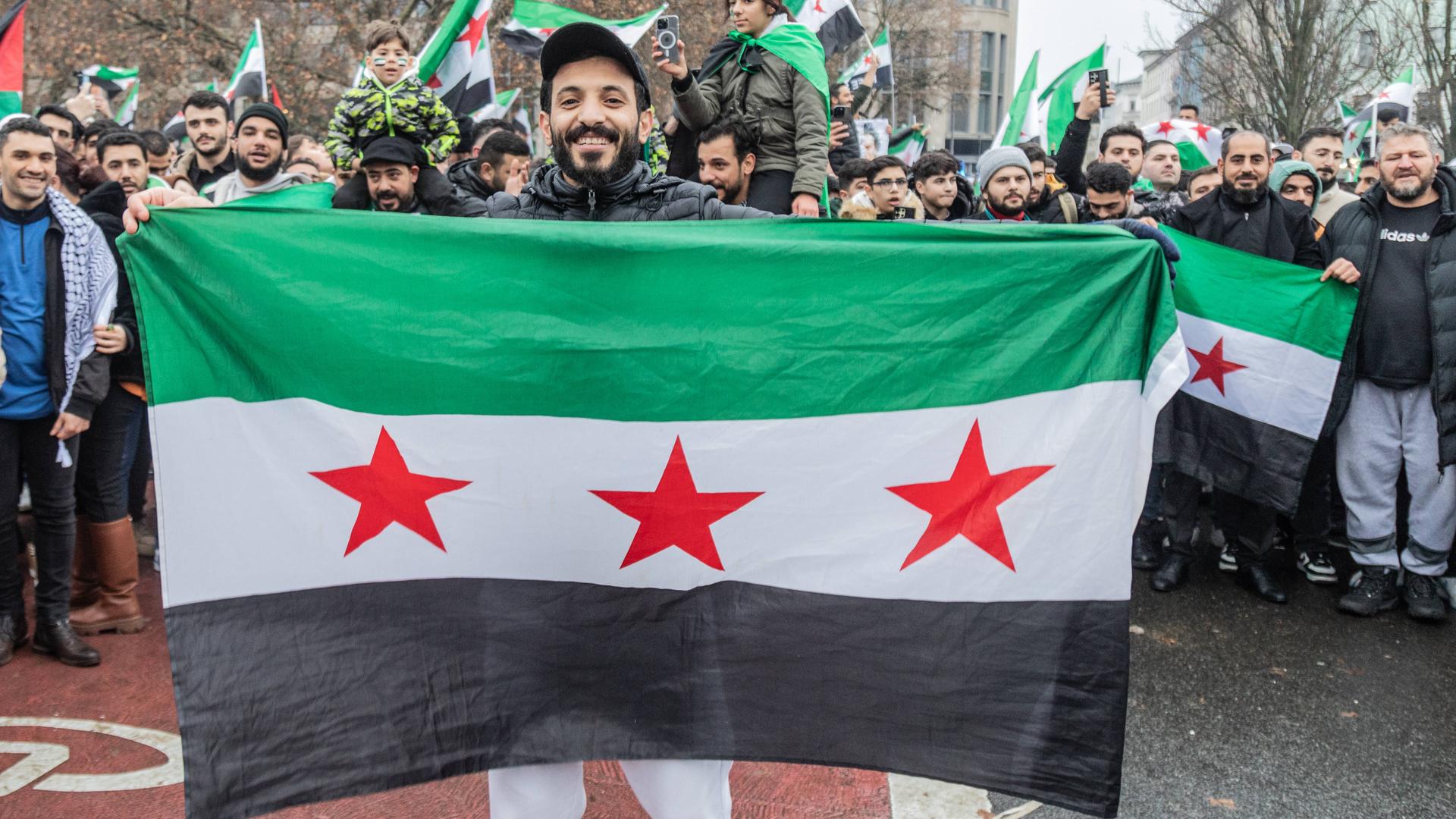 Ein junger Mann hält während der Feier eine Flagge der Freien Syrischen Armee hoch.