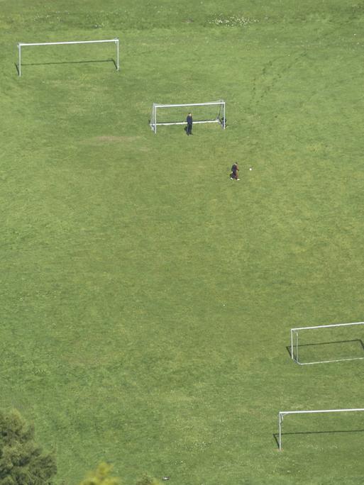 Ein Fußballplatz von oben. Zwei Menschen sind als kleine Figuren zu erkennen.