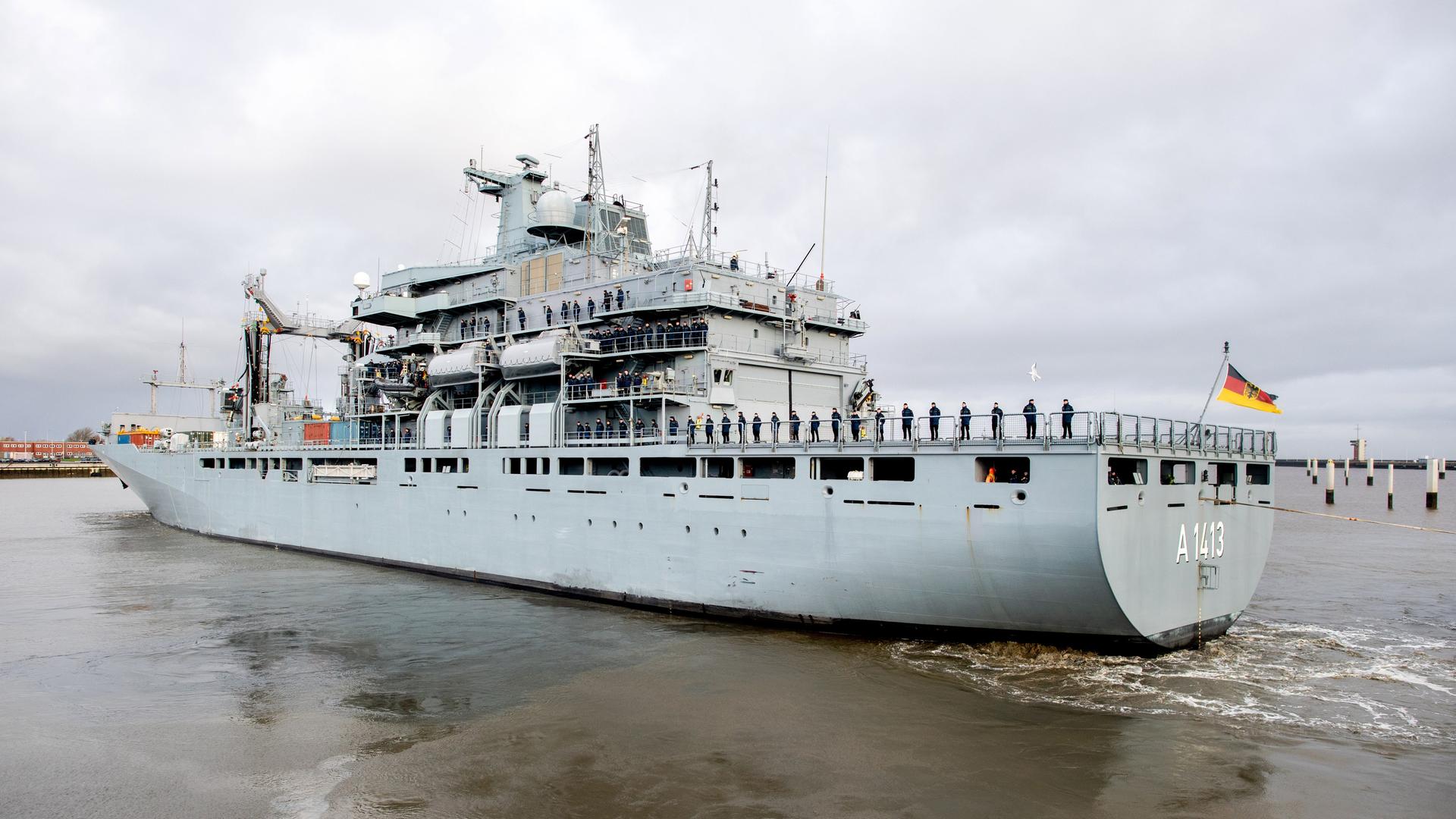 Blick von schräg hinten auf das in einen Hafen einfahrende Schiff.