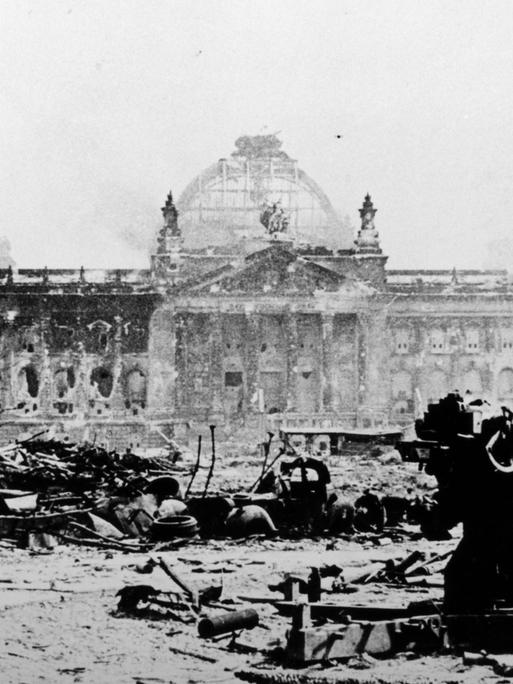 Ein verblichenes schwarz-weiß Foto des zerstörten Reichtagsgebäudes in Berlin im Mai 1945.