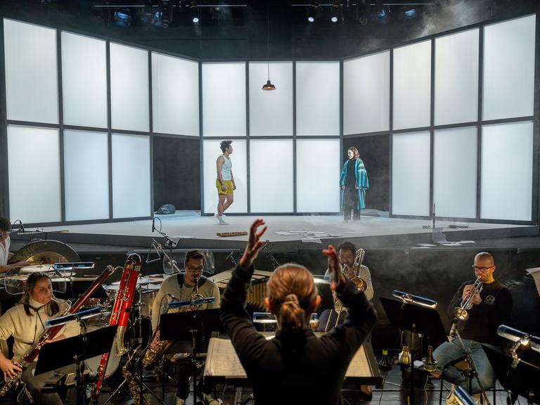 Ein Blick auf die Bühne mit zwei Darstellern und Musiker im Orchestergraben unter Leitung von Claire Levacher