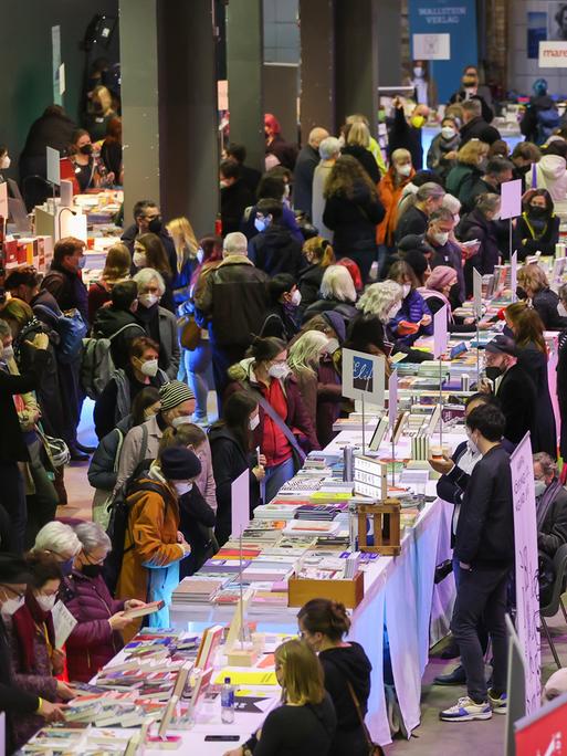 Publikum bei der Pop-Up-Buchmesse in Leipzig an Tischen mit Büchern.